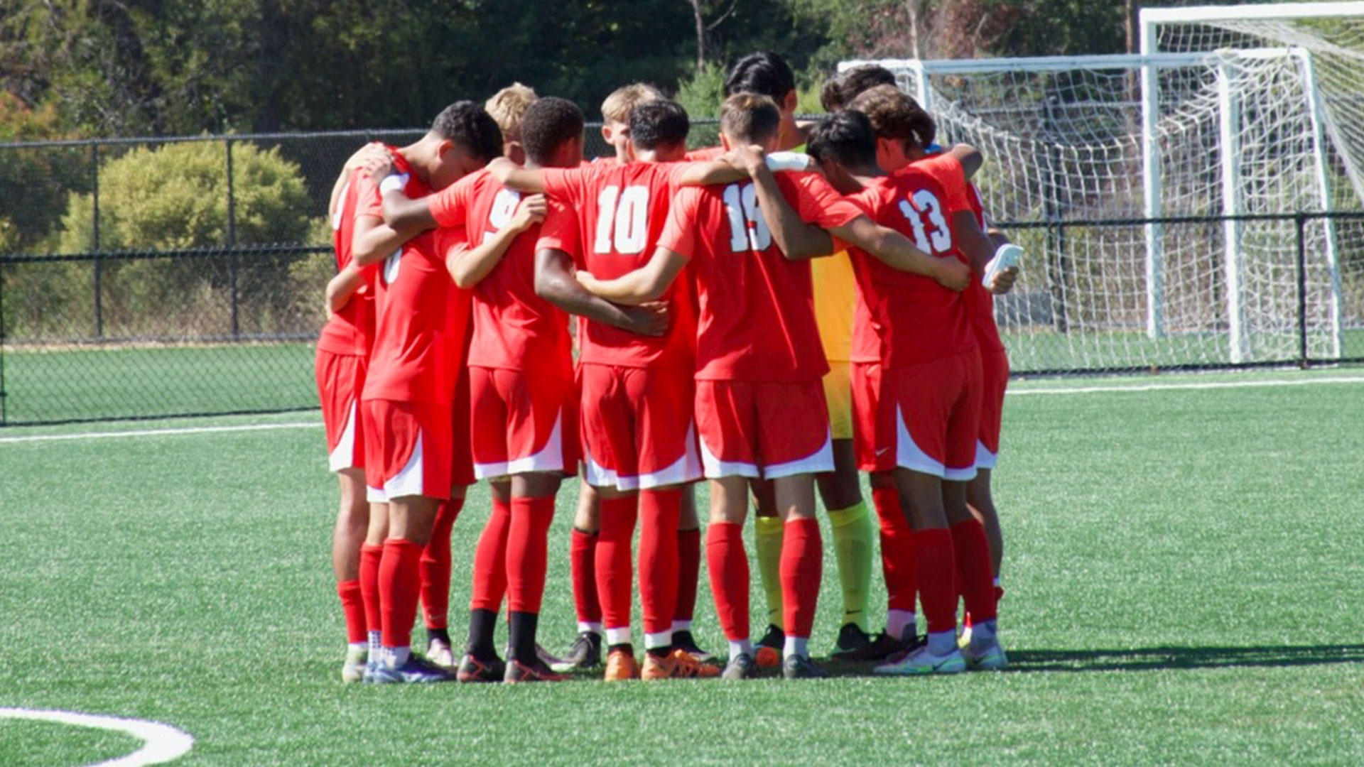 team in red jerseys in a huddle
